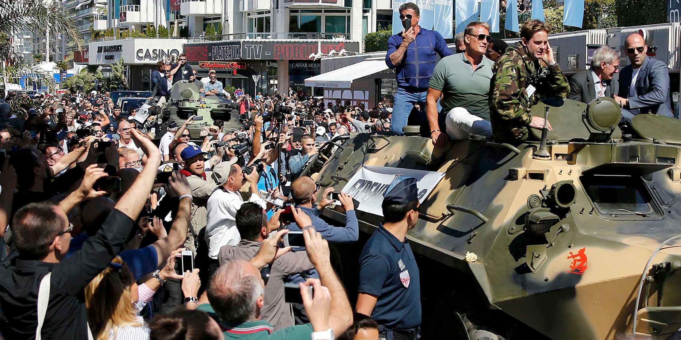 Cast members Sylvester Stallone, Dolph Lundgren, Harrison Ford and Jason Statham pose on a tank as they arrive on the Croisette to promote the film &quot;The Expendables 3&quot; during the 67th Cannes