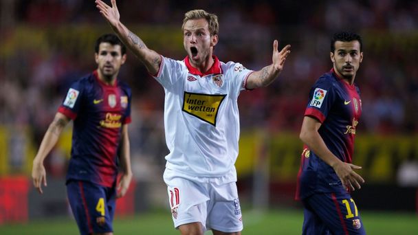 Fotbalisté Barcelony Cesc Fabregas (vlevo) a Pedro Rodriguzez (vpravo) sledují vztekajícího se Ivana Rakitiče v utkání španělské La Ligy 2012/13 se Sevillou.