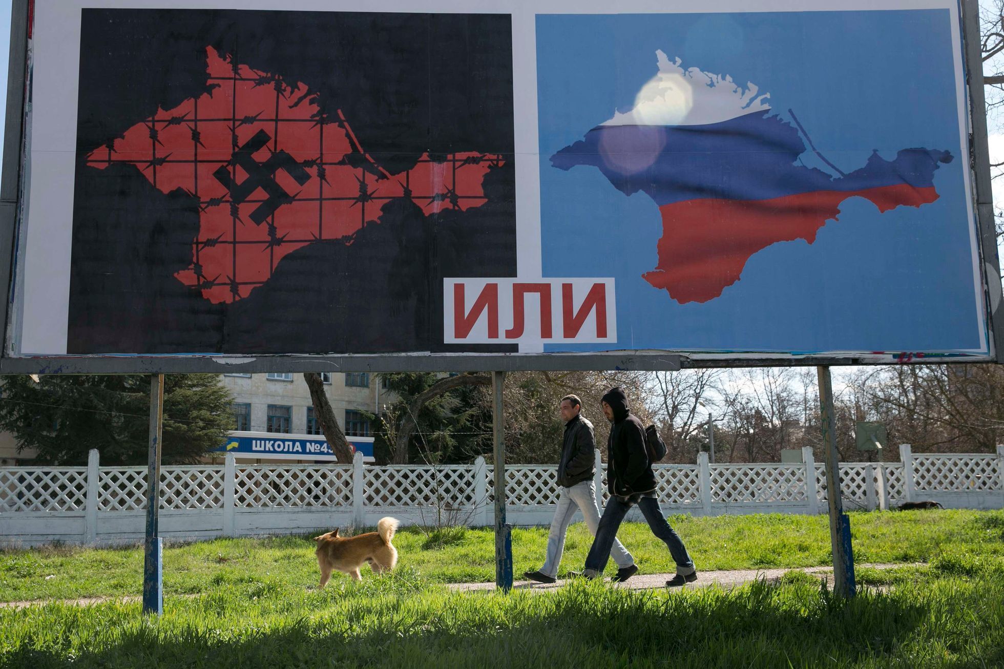 People walk past a poster calling people to vote in the upcoming referendum, at the Crimean port of Sevastopol