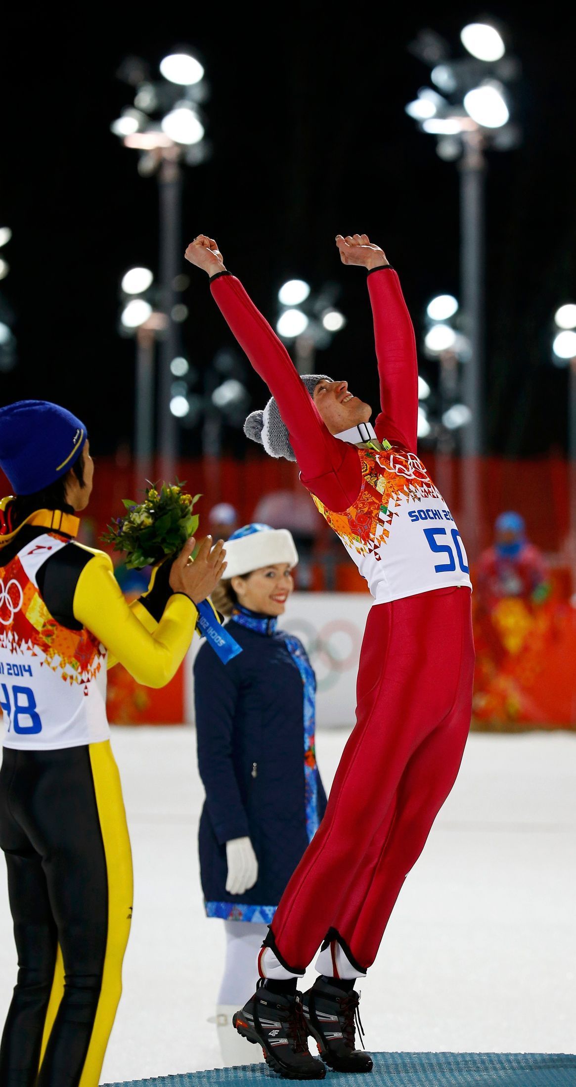 Winner Poland's Stoch is applauded by second-placed Japan's Kasai as he celebrates on the podium during the flower ceremony after his victory in the men's ski jumping individual normal hill final even
