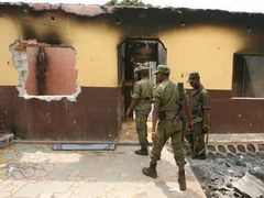 Guinejské bezpečnostní jednotky hlídkují nedaleko opozicí vypálené policejní stanice v Conakry