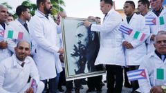 Kubánští doktoři s fotografií Fidela Castra se loučí se veřejností před cestou do Itálie.