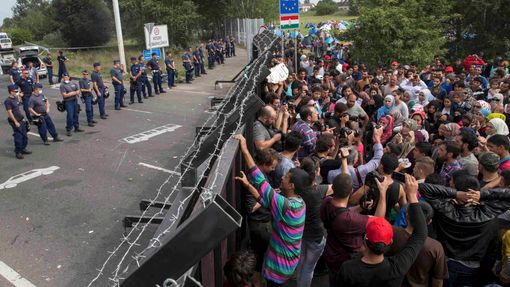Běženci se tísní před jedním z plotů na srbsko-maďarské hranici.