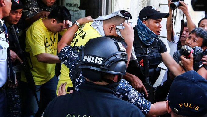 Od filipínského soudu odvádějí jednoho z policistů obviněných ze zabití 17letého mladíka.