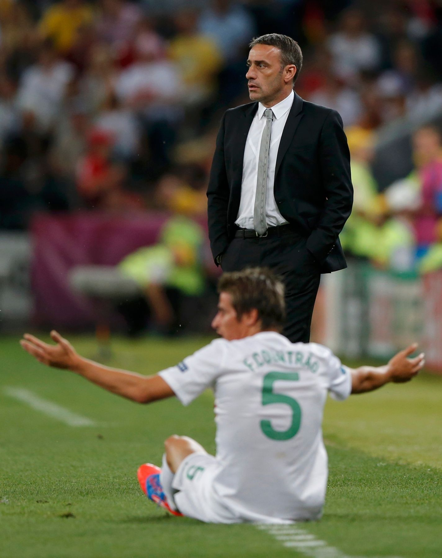 Sedící portugalský fotbalista Fabio Coentrao si stěžuje na benevolenci rozhodčího a nad ním stojí trenér Paulo Bento během semifinále na Euru 2012.