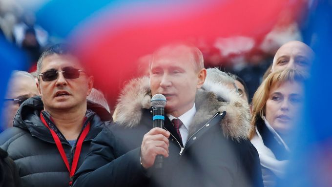 Vladimir Putin pěje státní hymnu na mítinku na stadionu v Lužnikách.
