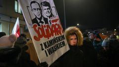 Protestující drží ceduli s podobiznami zadržených bývalých poslanců Mariusze Kaminského a Macieje Wasika poblíž policejní stanice Grochow ve Varšavě v Polsku dne 9. ledna 2023.