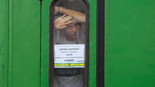 Muž vyhlíží z okna vlaku na nádraží v maďarském Bicske. Uprchlíci odmítají vystoupit a zaregistrovat se ve zdejším detenčním táboře.