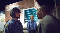A protester confronts a police officer outside the City of Ferguson Police Department and Municipal Court in Ferguson