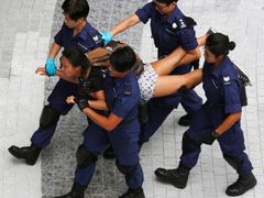 Demonstrantka, která protestovala u vládního komplexu v Hongkongu, je odváděna policií.