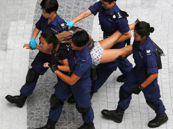 Politické nepokoje v Hongkongu Policie odvádí demonstrantku v Hongkongu