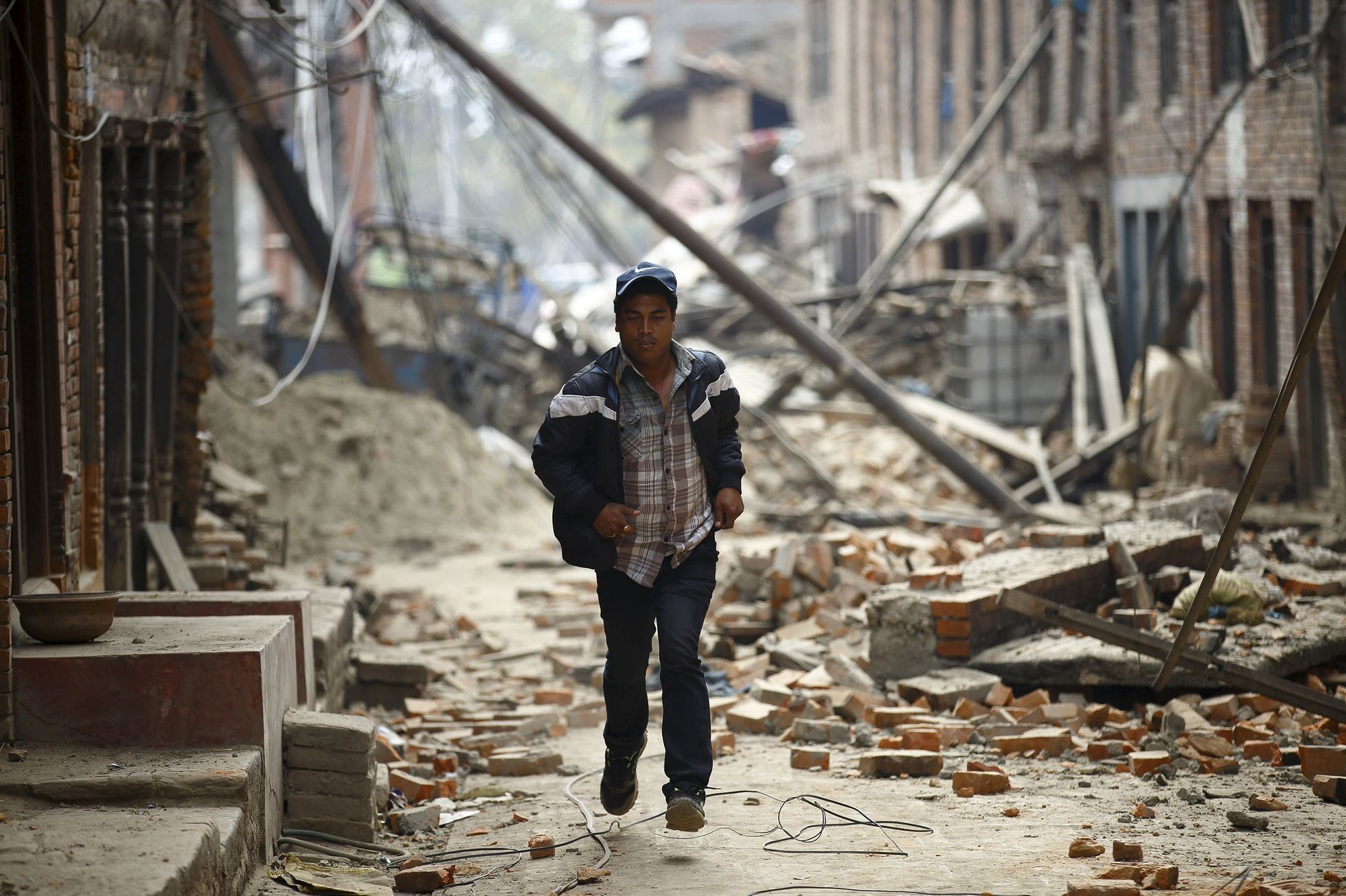 Muž běží zničenou ulicí ve městě Baktapúr.