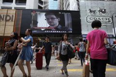 People cross a street in front of a monitor showing file footage of Edward Snowden, a former contractor for the U.S. National Security Agency (NSA), with a news tag (L) saying he has left Hong Kong, outside a shopping mall in Hong Kong June 23, 2013. Snowden left Hong Kong on a flight for Moscow on Sunday and his final destination may be Ecuador or Iceland, the South China Morning Post said. REUTERS/Bobby Yip (CHINA - Tags: POLITICS MEDIA) Published: Čer. 23, 2013, 8:35 dop.