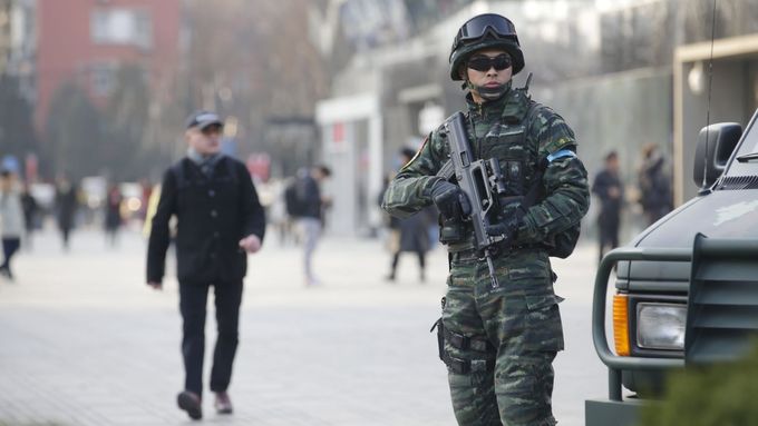 Člen policejního komanda hlídá nákupní středisko v centru Pekingu.