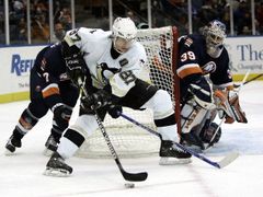 Hokejista Pittsburgu Penguins Sidney Crosby (uprostřed) objíždí branku Ricka DiPietra z New York Islanders.