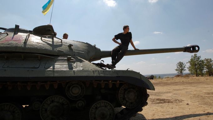 Ukrajinský voják sedí na tanku, který armáda ukořistila proruským separatistům.
