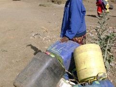 Keňská žena se snaží stopnout automobil, aby mohla zajet pro vodu, které je momentálně v severovýchodní Keňi nedostatek.