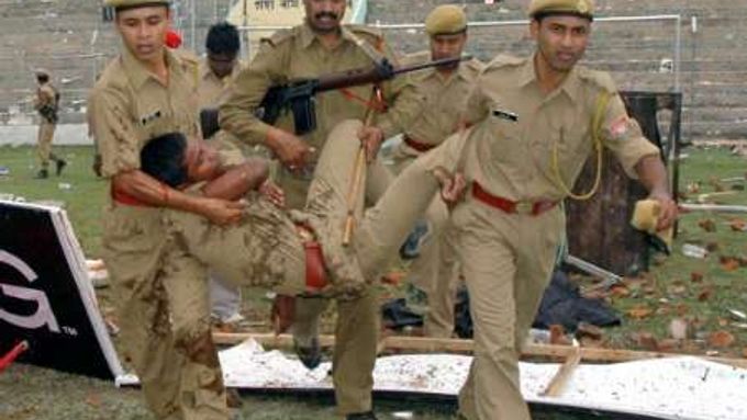 Policisté odnášejí zraněného kolegu při nepokojích, které vypukly po zrušení kriketového zápasu v indickém Guwahati.