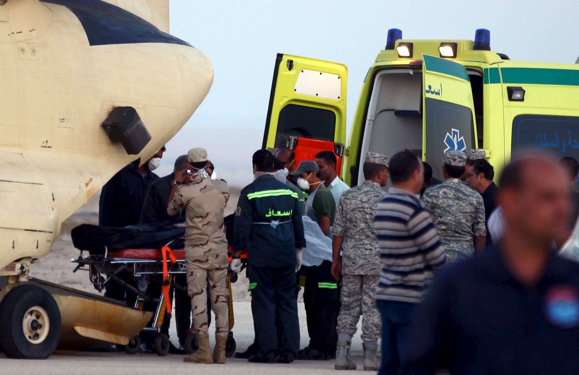 Egyptští vojáci a záchranáři nakládají do sanitky tělo jedné z obětí z havarovaného letadla.