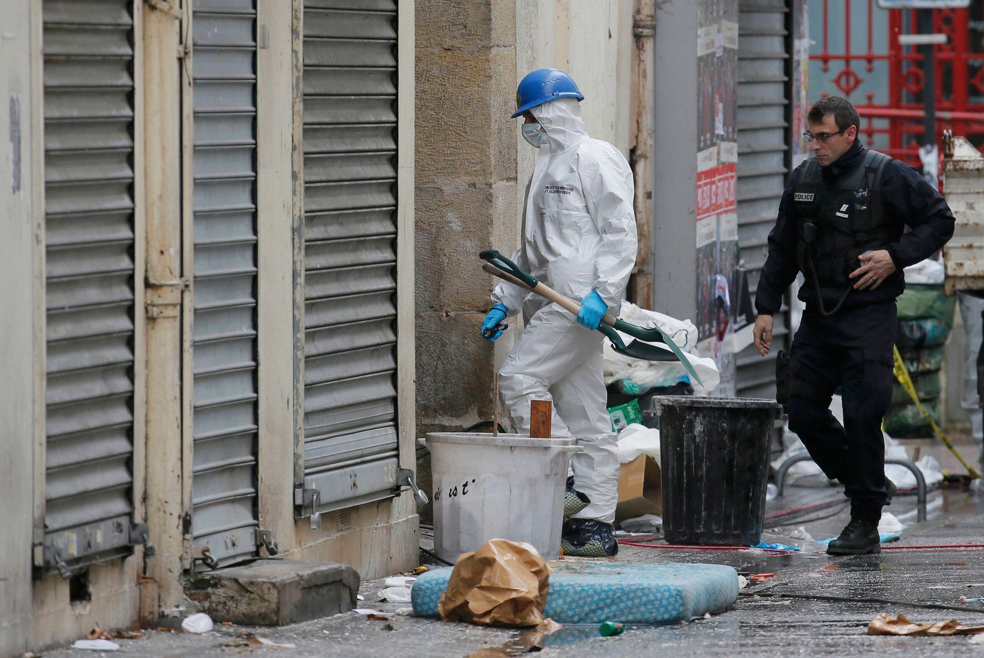 Francouzský policista a forenzní expert vcházejí do domu v Saint-Denis