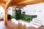 V přízemí je velká společenská místnost s kuchyní a pecí s tmavě zelenými, keramickými obklady.