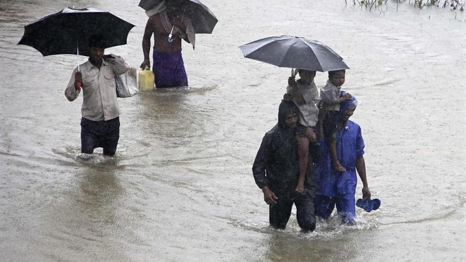 Vesničané na zaplavené cestě v oblasti Khurda na východě Indie.