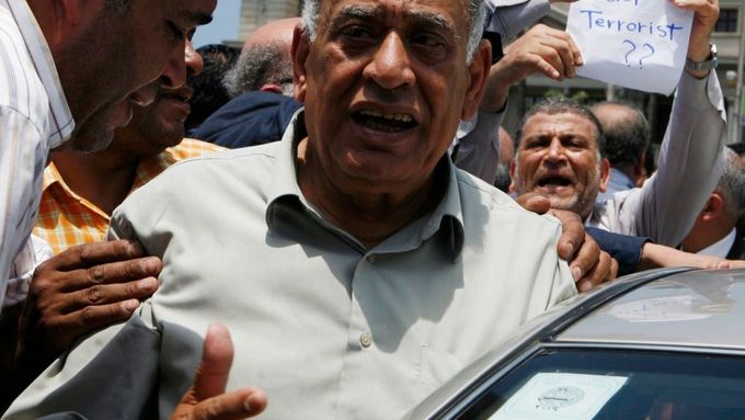 Otec zavražděné Sherbiniové na jejím pohřbu v egyptském městě Alexandrii. Muž za ním má v ruce nápis "Kdo je tady terorista?"