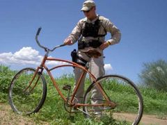 Příslušník pohraniční stráže v Arizoně si prohlíží kolo,které poblíž hranice zanechal jeden z nelegálních imigrantů.