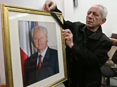 Člen Srbské socialistické strany vyvěšuje v Bělehradě smuteční portrét.