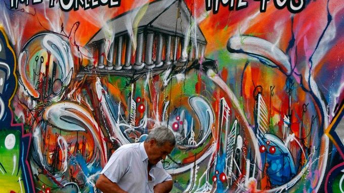 Muž prochází kolem graffiti znázorňující ekonomickou situaci v Evropě. Momentka z Lisabonu.