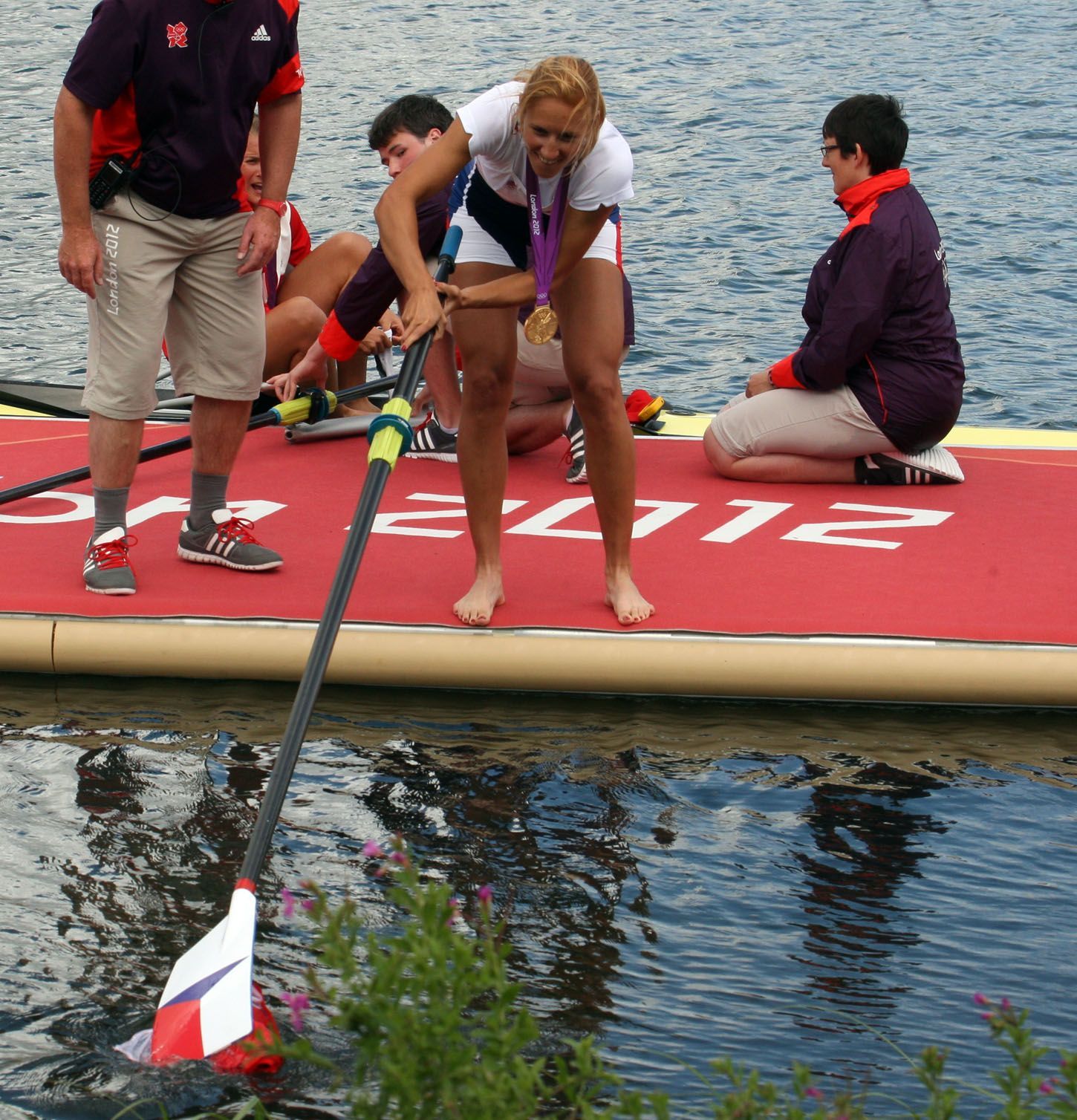 Česká veslařka Miroslava Knapková (uprostřed) slaví zlatou medaili a loví z vody českou vlajku na OH 2012 v Londýně.