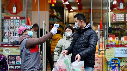 Lidé vycházející z obchodu ve Wu-chanu podstupují měření teploty. Město je kvůli epidemii stále v karanténě.