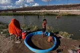 Nafukovací bazén slouží dětským hrám u řeky Rio Bravo. V pozadí plot, který odděluje Mexiko a USA.