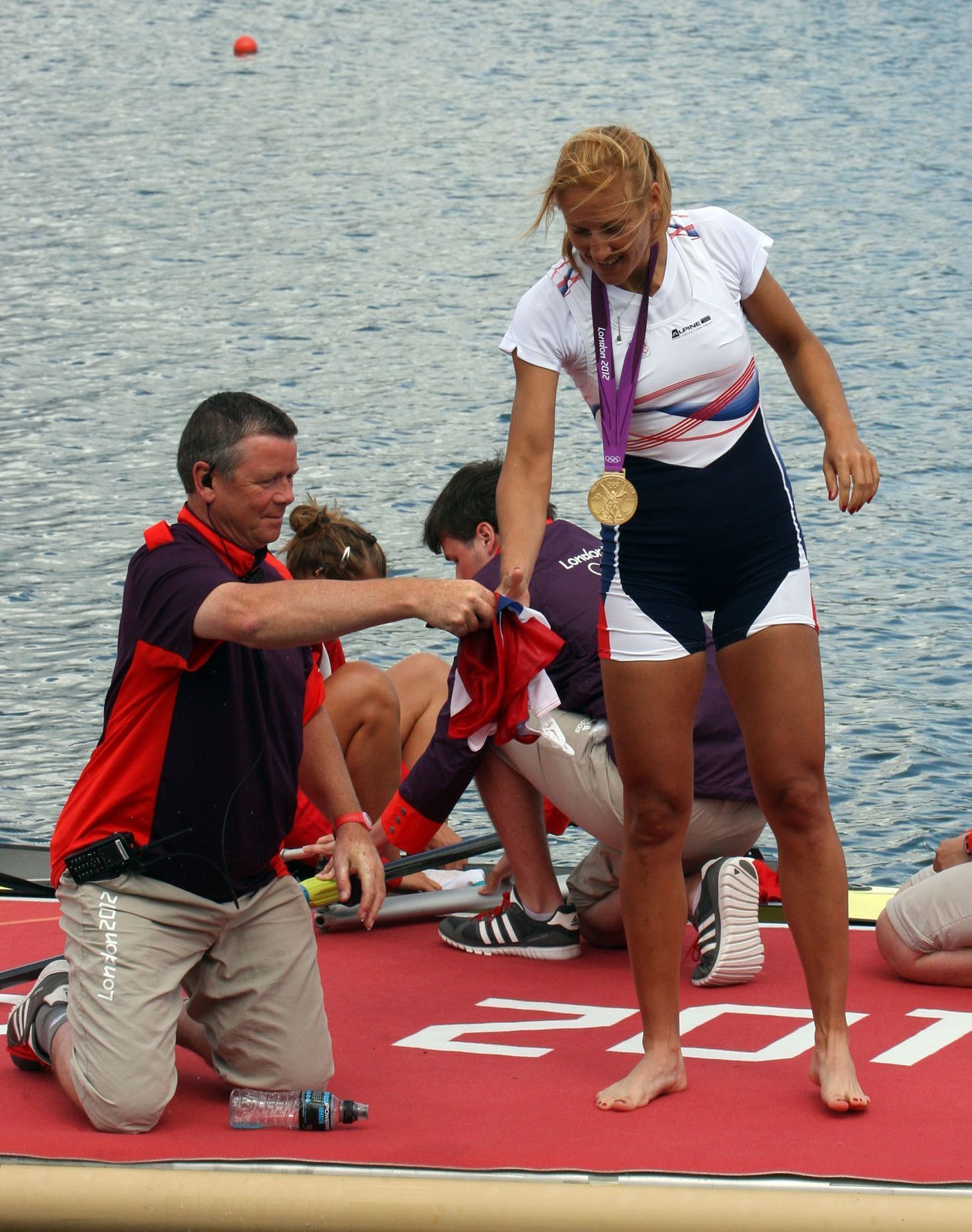 Česká veslařka Miroslava Knapková (uprostřed) slaví zlatou medaili a loví z vody českou vlajku na OH 2012 v Londýně.