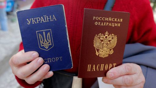 Žena drží v rukou pasy Ukrajiny a Ruska.