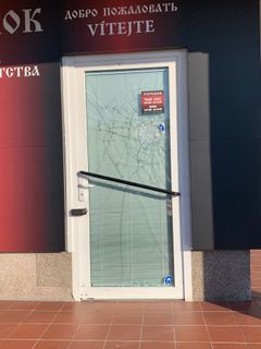 Rozbité dveře do prodejny potravin na pražském sídlišti Hůrka. 
