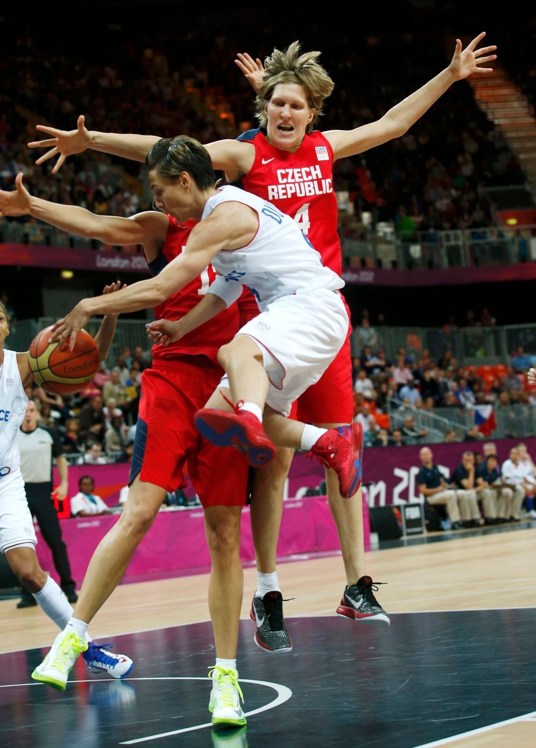 Česká basketbalistka Jana Veselá (vpravo) skáče nad Francouzkou Celine Dumercovou ve čtvrtfinále na OH 2012 v Londýně.