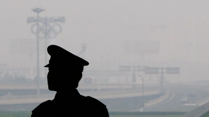 Policista shlíží na pekingské letiště. Skrze smog skoro není vidět.