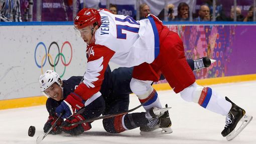 Team USA's Zach Parise (L) and Russia's Alexei Yemelin battle for the puck during the first period of their men's preliminary round ice hockey game at the Sochi 2014 Wint