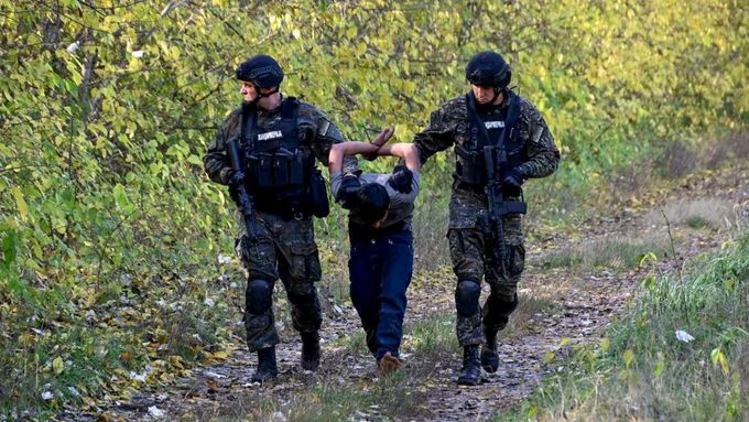 Na snímku poskytnutém srbským ministerstvem vnitra policisté zadržují migranta poblíž hranic mezi Srbskem a Maďarskem.
