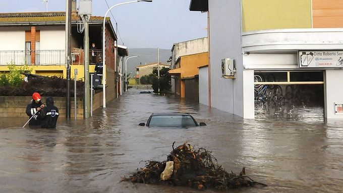 Záchranáři v ulicích městečka Uras, které po prudké bouři zaplavila voda.