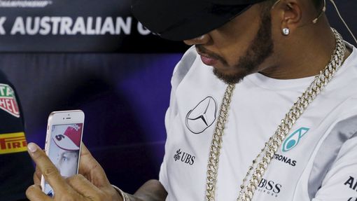 Mercedes F1 driver Lewis Hamilton takes a mobile phone picture of Ferrari F1 driver Sebastian Vettel during a news conference at the Australian Formula One Grand Prix in