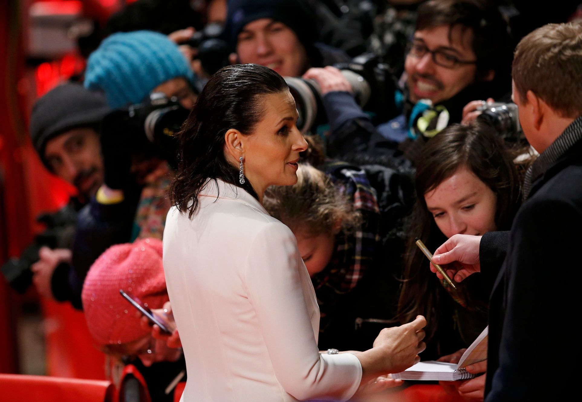 Actress Binoche signs autographs as she arrives on the red carpet for the screening of the movie 'Nobody Wants the Night', during the opening gala of the 65th Berlinale International Film Festival, in