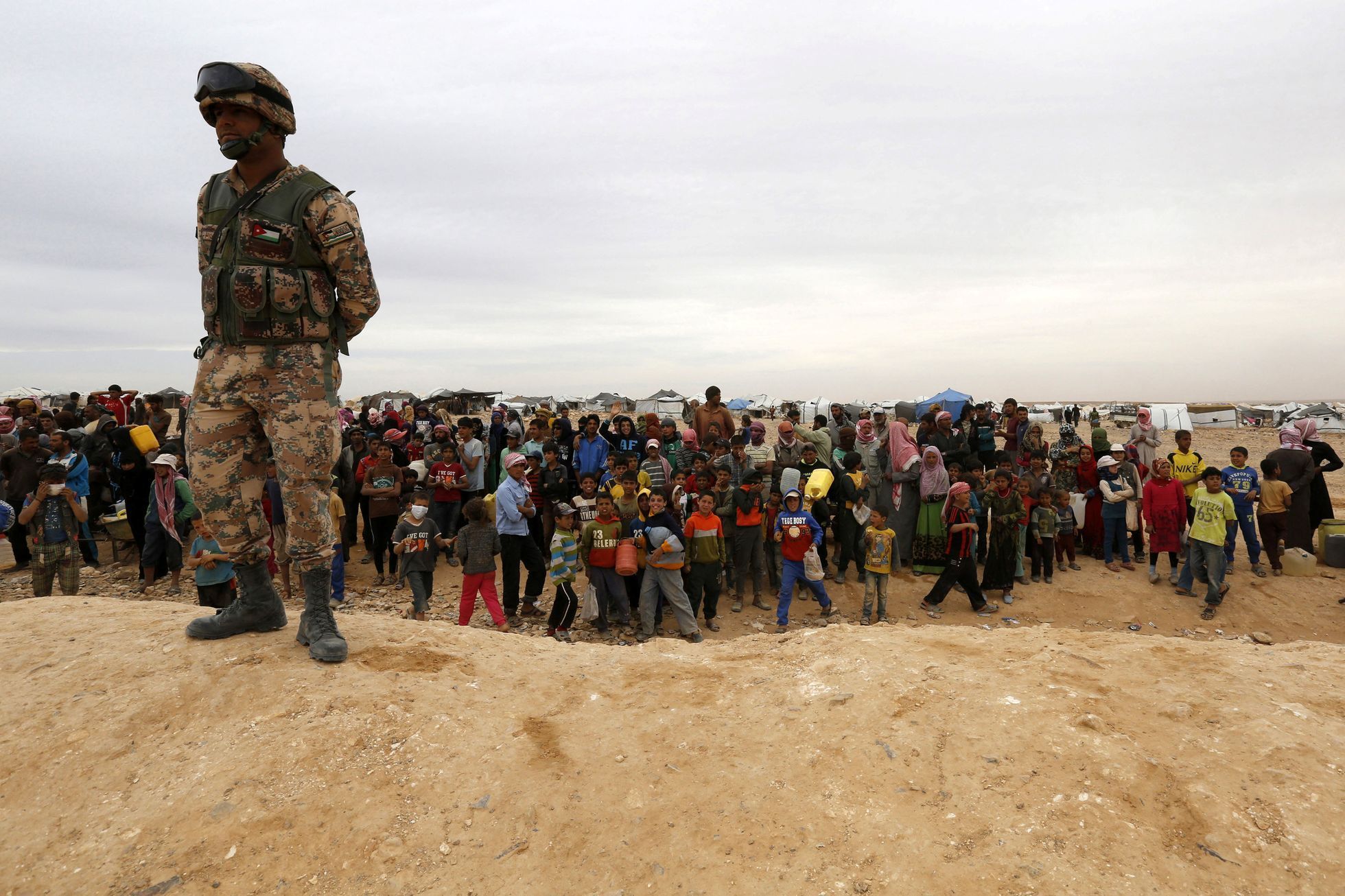 Jordánský voják hlídá uprchlíky na syrsko-jordánské hranici.