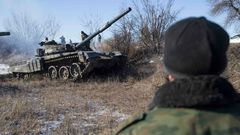 A man watches a tank of the separatist self-proclaimed Donetsk People's Republic Army manoeuvre near a checkpoint on the road from Vuhlehirsk to Debaltseve