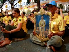 Thajci čekají před královským palácem na korunovaci krále, někteří v ruce třímají i panovníkův portrét.