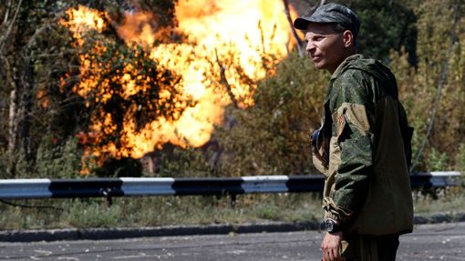 Proruský separatista u hořící čerpací stanice, kterou údajně zasáhl dělostřelecký granát. Armáda tvrdí, že ostřelování mají na svědomí povstalci. Ti obviňují vojáky.