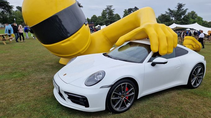Socha závodníka v nadživotní velikosti, která drží Porsche 911, byla uprostřed velké odpočinkové louky.