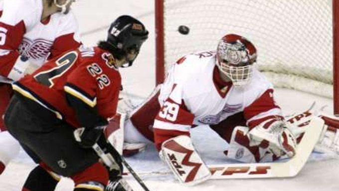 Daymond Langkow z Calgary (v červeném) dává gól do sítě brankáře Detroitu Dominika Haška. Vlevo je bek Red Wings Niklas Krönwall.