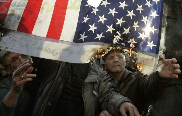 Demonstranti zapalují v Bělehradě americkou vlajku. | Foto: Reuters